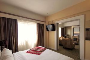 a hotel room with a bed with a mirror and a television at Shahzan Hotel Kuantan, Trademark Collection by Wyndham in Kuantan