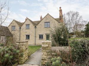 an old stone house with a stone wall at High Cogges Farm Holiday Cottages in Witney