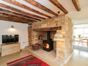 a living room with a stone fireplace and a tv at High Cogges Farm Holiday Cottages in Witney
