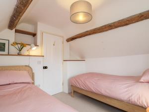 two beds in a room with white walls at High Cogges Farm Holiday Cottages in Witney