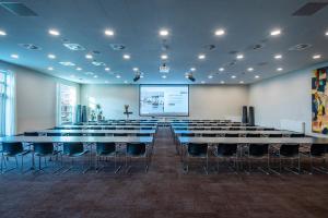 a conference room with tables and chairs and a screen at Comwell Middelfart in Middelfart