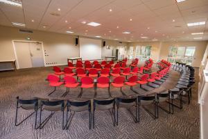 VernantoisにあるGolf Domaine Du Val De Sorneの大きなテーブルと赤い椅子が備わる会議室を利用できます。