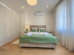 um quarto com uma cama grande e lençóis verdes em Ultralux magnolia city center bestern em Szeged