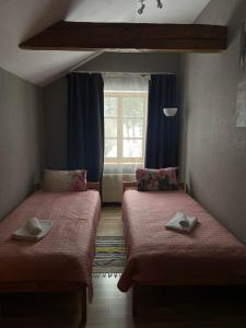 two beds in a small room with a window at Spēlmaņu krogs in Alsunga