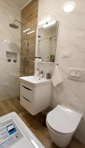 a white bathroom with a toilet and a sink at Apartman Leona in Lovran