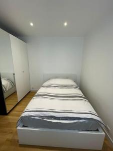 Ce lit se trouve dans un dortoir doté d'un mur blanc. dans l'établissement Paris Centre CLAMART Hôpital PERCY APPART 2 pièces TRÈS Lumineux Grand, à Clamart