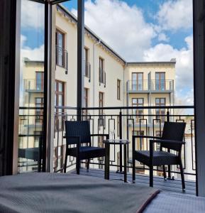 a balcony with two chairs and a table and a building at Hotel KAISERHOF in Bitterfeld