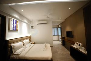 a bedroom with a large bed and a television at Hotel Midland, Nanded in Nānded