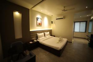 a bedroom with a bed and a desk and a chair at Hotel Midland, Nanded in Nānded