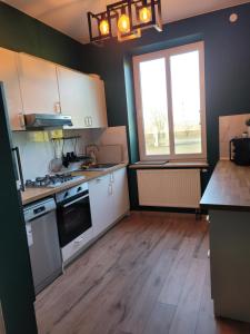 a kitchen with white cabinets and a large window at Dworek Sobieskiego in Skierniewice