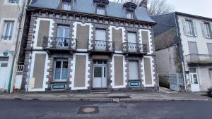 un vieux bâtiment avec des finitions blanches et brunes dans une rue dans l'établissement Villa de la dore, à Le Mont-Dore