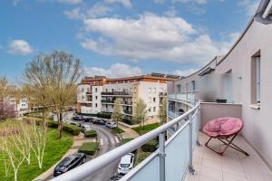 Un balcón con una silla rosa y una calle en Le Cozy Garden - Mayvenn, en Saint-Thibault-des-Vignes