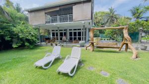 two white chairs and a swing in a yard at Villa cork in Galle