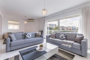 a living room with two couches and a table at Stunning - SunnySide 3-Bedroom in Sliema