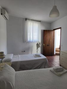 Un dormitorio blanco con dos camas y un ventilador. en Habitaciones Martín, en San José