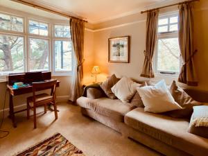 a living room with a couch and a desk and windows at Cheswood in Lynmouth