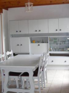 a white kitchen with a white table and chairs at le chalet in Saint-Nabord