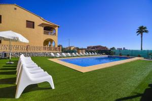 a pool with white lounge chairs and a building at Villa Ambar - PlusHolidays in Calpe