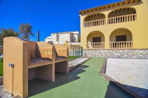 un gran edificio amarillo con un patio verde en Villa Ambar - PlusHolidays, en Calpe