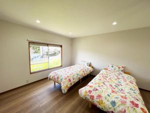 two beds in a room with a window at ゆふの音 in Yufuin