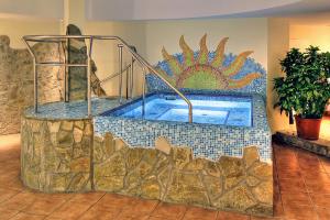 ein Swimmingpool in einem Raum mit einer gefliesten Wand in der Unterkunft Hotel Mediterran Budapest in Budapest