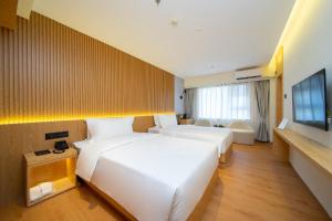 a hotel room with two beds and a television at MARHAUS Hotel Beijing Road Tian-Zi Pier Store in Guangzhou