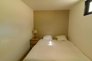um pequeno quarto com uma cama com duas almofadas em Pyla sur mer proche plages appartement avec piscine em Pyla-sur-Mer