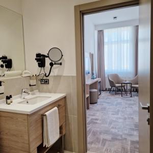 La salle de bains est pourvue d'un lavabo et d'un miroir. dans l'établissement Hotel KAISERHOF, à Bitterfeld