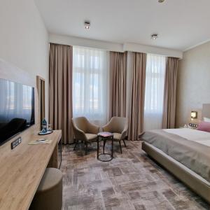 una camera d'albergo con letto, scrivania e sedie di Hotel KAISERHOF a Bitterfeld