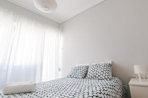 Habitación blanca con cama y ventana en Maré Alta Alojamentos en Peniche