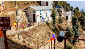 a toy house on a hill with a street sign and balloons at Dev Bhoomi Resort in Kanatal
