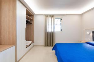 um quarto com uma cama azul e uma janela em Mare del Sud em Donnalucata
