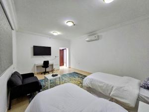 Spacious Apartment في مكة المكرمة: غرفة نوم بسريرين وتلفزيون على الحائط
