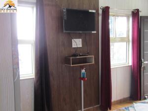 a room with a television on a wall with windows at Dev Bhoomi Resort in Kanatal