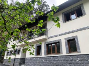 a house with a balcony and trees at Casa Rural en Santa Cruz-Mieres in Bustiello