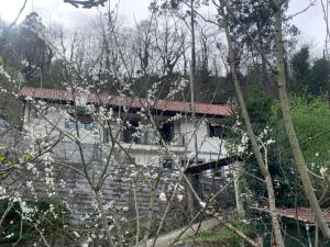 a white house with a red roof and some trees at Casa Rural en Santa Cruz-Mieres in Bustiello