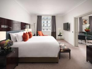 a hotel room with a large white bed and a desk at Sofitel London St James in London