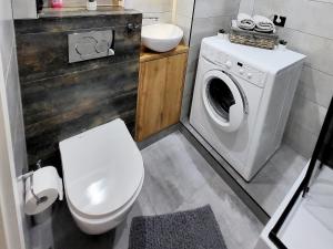 a bathroom with a toilet and a washing machine at Przytulnie w Szczytnie in Szczytno
