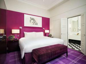 ロンドンにあるソフィテル ロンドン セント ジェームスの紫の壁のベッドルーム1室(大きな白いベッド1台付)
