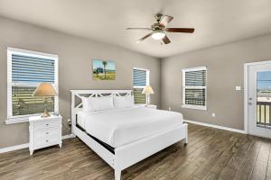1 dormitorio con cama blanca y ventilador de techo en The Blue Pelican, en Corpus Christi