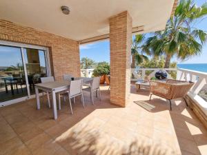een patio met een tafel en stoelen en de oceaan bij Frontline Beach Villa Playa Flamenca in Orihuela