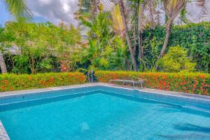 a swimming pool in front of a garden with flowers at Casa Iorio in Jacó