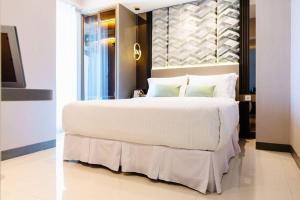 una camera da letto con un grande letto con lenzuola e cuscini bianchi di kimaya at Benson Pakuwon Mall a Surabaya