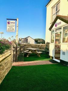 a picnic table in front of a building with green grass at Pendrin Guest House in Tintagel