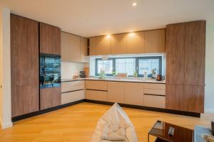 Designer Apartment in Aviatiei Tower في بوخارست: مطبخ كبير مع دواليب خشبية وطاولة
