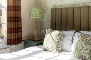 a bed with two pillows and a lamp on a table at The Richard Onslow in Cranleigh