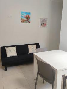 Una sala de estar con un sofá negro y una mesa. en My Home Lampedusa, en Lampedusa 5 fotos más