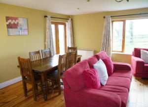 a living room with a red couch and a table at Dingle Courtyard Holiday Homes 3 Bed in Dingle
