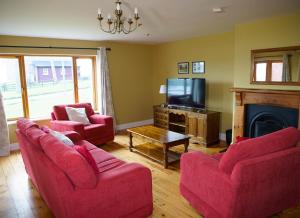 a living room with two red chairs and a tv at Dingle Courtyard Holiday Homes 3 Bed in Dingle