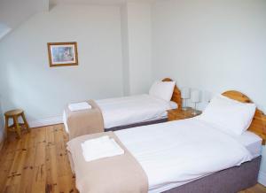 Duas camas num quarto com lençóis brancos e pisos em madeira em Dingle Courtyard Holiday Homes 3 Bed em Dingle